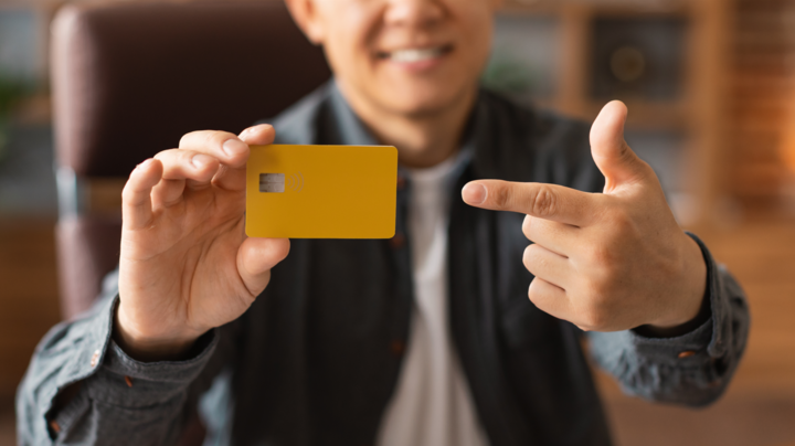 Glad middle aged asian man pointing finger at business credit for startups card in home office interior, cropped